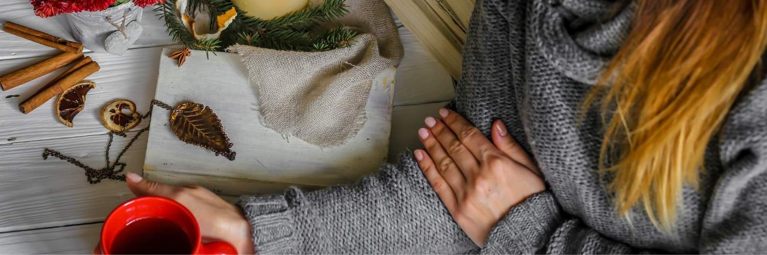 Une femme tenant une tasse contenant une boisson chaude. A côté d'elle se trouve de l'ashwaganda. 