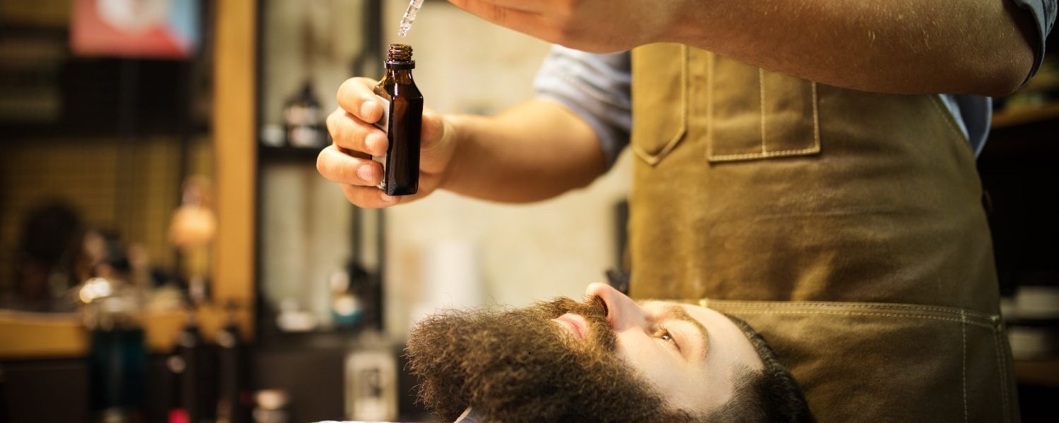 Un homme en train de s'appliquer de l'huile sur la barbe à l'aide d'une pipette