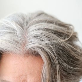 Photo d'une chevelure féminine grisonnante, avec de nombreux cheveux blancs