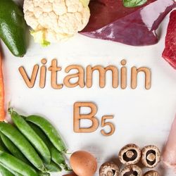 L'inscription "vitamin B5" formée avec des lettres en bois, entourée de légumes comme des petits pois, des champignons, du chou-fleur, des œufs, et de la viande.