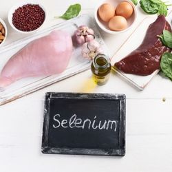 Sources alimentaires de sélénium, comprenant de la viande, des œufs, des noix et de l'huile d'olive, autour d'une ardoise avec l'inscription 'Selenium'