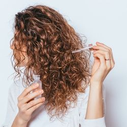 Une femme en train de s'appliquer un complément sur les cheveux à l'aide du pipette