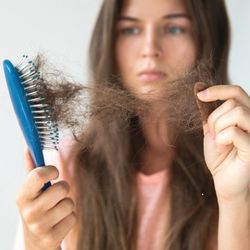 Une femme en train de retirer les cheveux perdus de sa brosse