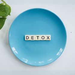 Une assiette contenant des dés de Scrabble disposés pour former le mot "DETOX".