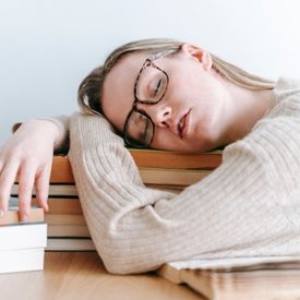 Photo d'une femme visiblement épuisée qui s'est endormi sur ses livres de révision