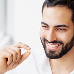 Image d'un homme souriant tenant entra ses mains gélules une gélule de complément alimentaire