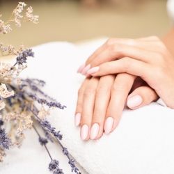 Une main avec des ongles éclatants posée sur un drap blanc