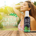 Un flacon de 100 ml d'aromaspray menthe eucalyptus posé sur une table en bois avec en arrière plan une femme se tenant les cheveux et inspirant