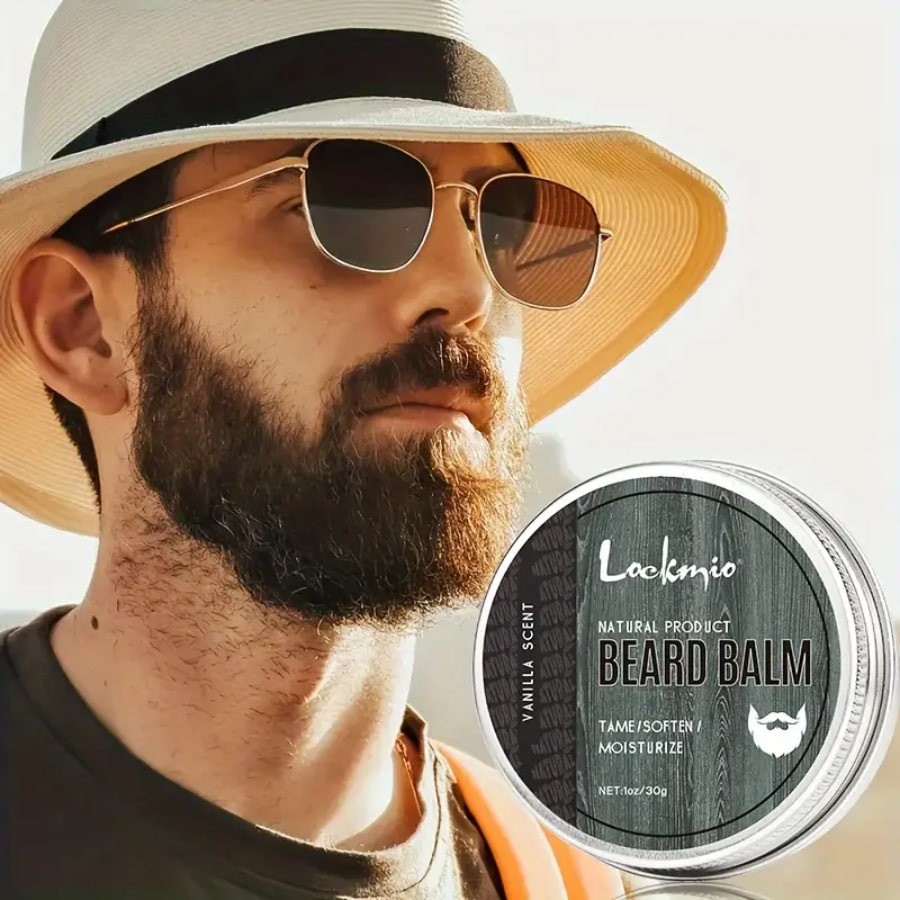 Photo d'un homme parfaitement rasé avec un chapeau et des lunettes de soleil posant à côté d'un Baume à Barbe au Squalane au parfum vanille