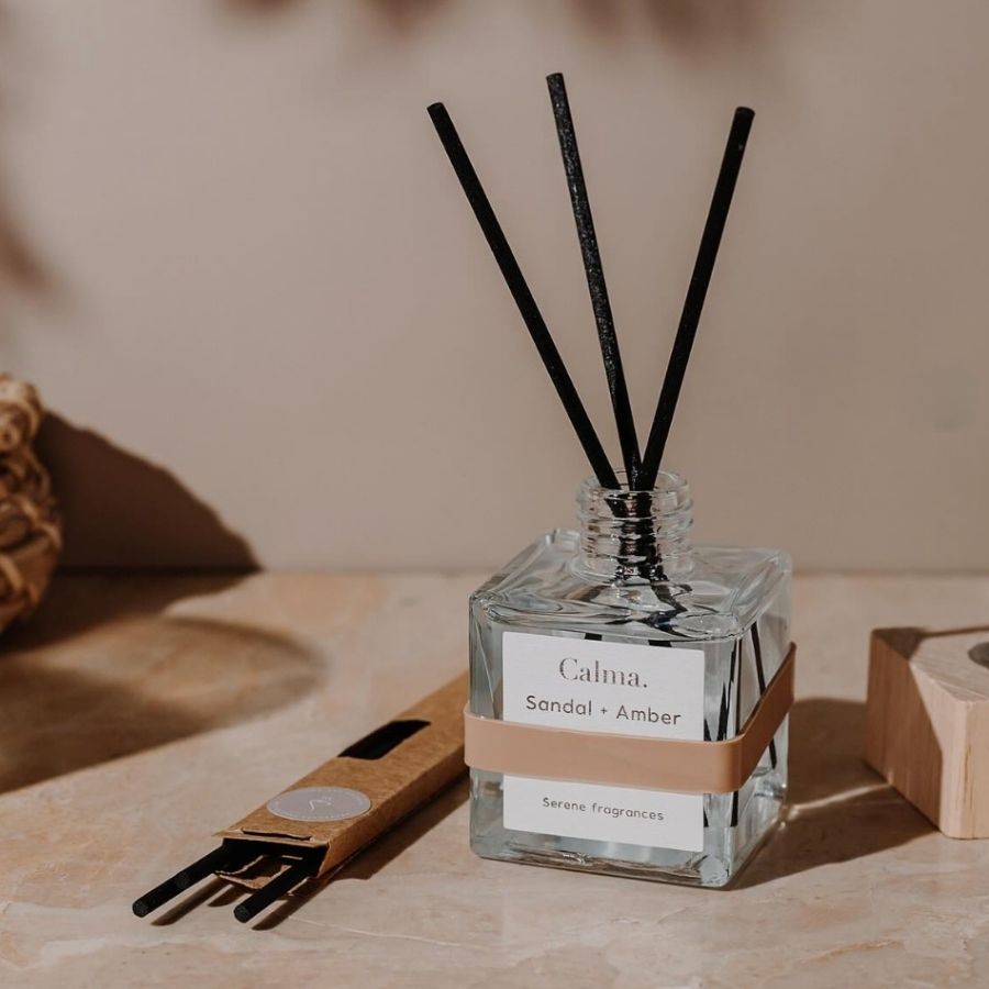 Un Diffuseur de parfum à bâtonnets senteur Bois de santal & Ambre, ouvert avec ses bâtonnets installés dedans, et posé sur une table en marbre.