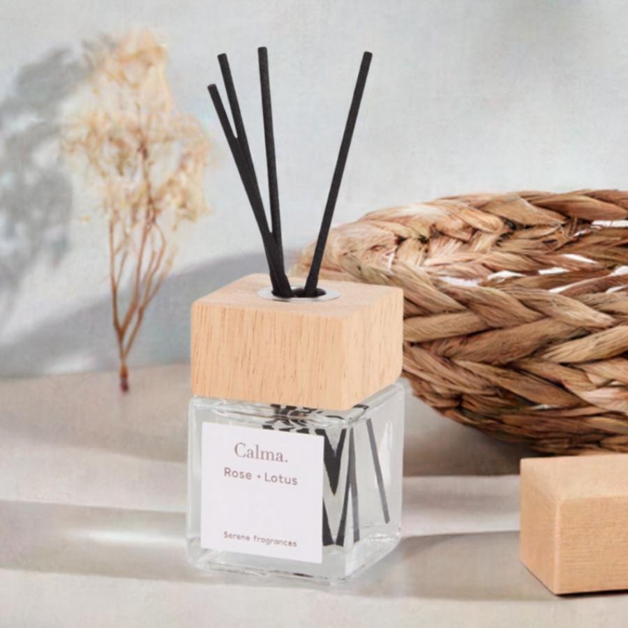 Un Diffuseur de parfum à bâtonnets senteur Rose & Lotus, devant un panier en osier et un bouquet de fleurs séchées