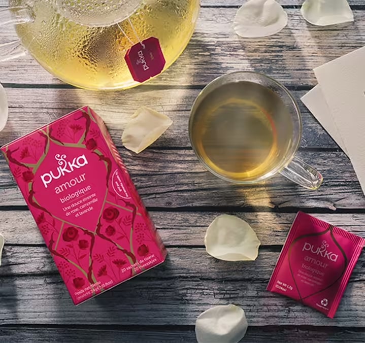 Une tasse d'infusion Amour Bio Pukka posée à côté de sa boite